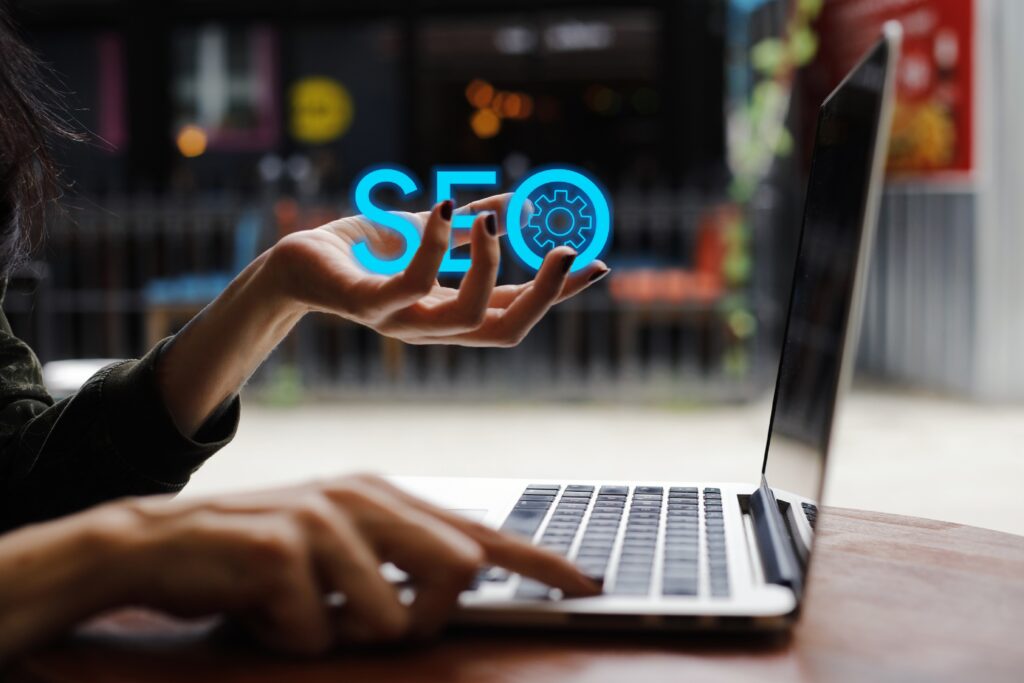 Grafika SEO nad dłonią użytkownika pracującego przy laptopie